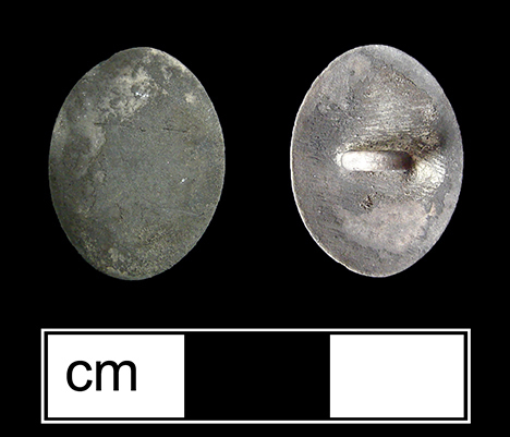 White metal oval link, possibly silver. There is no evidence of decoration, but the link has been burned and is covered in soot.